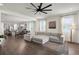 Open-concept living room with hardwood floors, large windows, and modern furniture, flowing into the kitchen at 2468 Varenna Loop, Kissimmee, FL 34741