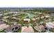 Aerial view of neighborhood homes surrounding a pond, lush greenery, and mature trees under a blue sky at 3010 Winding Trl, Kissimmee, FL 34746