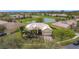An aerial view of a home with a tile roof, and a well manicured front yard that is surrounded by a pond and lush greenery at 3010 Winding Trl, Kissimmee, FL 34746
