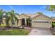Charming single-story home boasts a tile roof, two-car garage, brick driveway, and lush landscaping with palm trees at 3010 Winding Trl, Kissimmee, FL 34746
