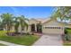 Charming single-story home boasts a tile roof, two-car garage, brick driveway, and lush landscaping with palm trees at 3010 Winding Trl, Kissimmee, FL 34746
