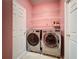 Laundry room featuring a pink wall, metal shelving, and modern LG washer and dryer at 3010 Winding Trl, Kissimmee, FL 34746