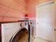 Bright laundry room with a pink wall, metal shelving, and modern LG washer and dryer at 3010 Winding Trl, Kissimmee, FL 34746