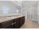 Bright bathroom featuring a double sink vanity with a large mirror and a glass-enclosed shower at 3188 Serendipity Way, Davenport, FL 33896
