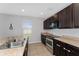 Modern kitchen with stainless steel appliances, dark cabinets, and tiled flooring at 3188 Serendipity Way, Davenport, FL 33896