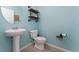 Stylish half bath with a pedestal sink, modern toilet, and decorative shelves at 3188 Serendipity Way, Davenport, FL 33896