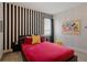 This vibrant bedroom showcases a unique striped wall, red bedding, and fun Disney-themed decor at 385 Southfield St, Kissimmee, FL 34747