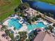 Aerial view of community pools, featuring sun loungers, a water slide and lots of shady palms at 3920 Reed Grass Pl, Kissimmee, FL 34746