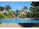 Inviting community pool features a zero entry, sun loungers, umbrellas, and palm trees at 3920 Reed Grass Pl, Kissimmee, FL 34746
