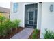 Close-up of front screened entry with a paved walkway, lush landscaping and a view of the home's facade at 3920 Reed Grass Pl, Kissimmee, FL 34746