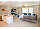 Open-concept living area featuring a kitchen island, modern decor, and sliding glass doors leading to the lanai at 3920 Reed Grass Pl, Kissimmee, FL 34746