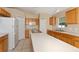 Well-lit kitchen featuring wood cabinetry, white appliances, and an island with a sink at 502 Woodland Creek Blvd, Kissimmee, FL 34744