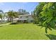 Expansive green lawn with a view of the two-story home featuring a metal roof and lush, tropical landscaping at 6100 Alligator Lake W Shr, St Cloud, FL 34771