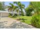Two-story home with lush landscaping, palm trees, and a metal roof, complemented by a concrete driveway at 6100 Alligator Lake W Shr, St Cloud, FL 34771
