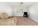 Bright living room with wood flooring, a large window with blinds, and a comfortable upholstered chair at 6100 Alligator Lake W Shr, St Cloud, FL 34771