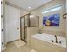 Modern bathroom with soaking tub, glass-enclosed shower, and neutral tile at 688 Cordoba Dr, Davenport, FL 33837