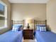 Inviting bedroom showcasing twin beds with blue accents, a bedside table with a lamp, and a serene atmosphere at 688 Cordoba Dr, Davenport, FL 33837