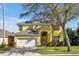 Two-story yellow home with a white garage door, arched entry, and solar panels at 8401 Secret Key Cv, Kissimmee, FL 34747