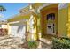 Close up view of the yellow home featuring an arched front entry and white garage door at 8401 Secret Key Cv, Kissimmee, FL 34747