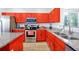 Modern kitchen featuring red cabinets, granite countertops, and stainless steel appliances at 8401 Secret Key Cv, Kissimmee, FL 34747