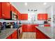 Bright kitchen featuring granite countertops, stainless steel appliances, and bold red cabinets at 8401 Secret Key Cv, Kissimmee, FL 34747