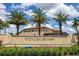 Windsor at Westside community entrance featuring a stone sign, palms, and lush landscaping under a bright, cloudy sky at 8936 Sydney Ave, Kissimmee, FL 34747