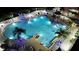 Stunning aerial view of the pool at night with palm trees, lounge chairs, and a bar area at 13427 Blue Heron Beach Dr # 1607, Orlando, FL 32821