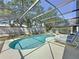 Inviting screened-in pool is surrounded by lounge chairs and mature trees at 1361 Rebecca Dr, Haines City, FL 33844