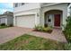 Inviting home featuring a brick driveway, two-car garage, and a charming covered entryway at 1371 Red Blossom Ln, Kissimmee, FL 34746