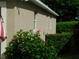 Side view of the property featuring stucco walls, white trim, and lush landscaping including hibiscus bushes at 2160 Addison Ave, Clermont, FL 34711