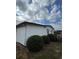 View of a side of the home's exterior showing white siding and manicured shrubbery at 222 Palmer Park Ln, Davenport, FL 33897