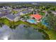 Scenic aerial view of condo community featuring a clubhouse, pool, pond, and lush landscaping at 2794 Club Cortile Cir # B, Kissimmee, FL 34746