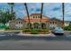 Attractive clubhouse entrance featuring stonework, a red tile roof, manicured shrubs, and a lush lawn at 2794 Club Cortile Cir # B, Kissimmee, FL 34746
