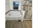 Bright bathroom features soaking tub, glass-enclosed shower, and wood-look tile floors at 2802 Glendive Dr, Kissimmee, FL 34758