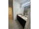 Bathroom featuring double sink vanity, granite countertops and a framed mirror with modern lighting at 2802 Glendive Dr, Kissimmee, FL 34758