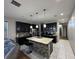 Modern kitchen featuring black cabinets, stainless steel appliances, and a large island with pendant lighting at 3100 Rocky River Rd, Kissimmee, FL 34746