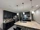 Stylish kitchen featuring black cabinets, granite countertops, stainless steel appliances, and a functional center island at 3100 Rocky River Rd, Kissimmee, FL 34746