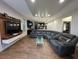 Spacious living room with wood-look floors, a large sectional sofa, and a modern entertainment center at 3100 Rocky River Rd, Kissimmee, FL 34746