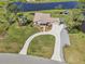 Stunning aerial view of waterfront home with lush landscaping, a long driveway, and attached garage at 3607 Hidden River Ln, Tavares, FL 32778