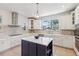 This kitchen features white cabinetry, a blue island, stainless appliances and a farmhouse style sink at 3607 Hidden River Ln, Tavares, FL 32778