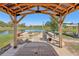 Picturesque outdoor area featuring a wooden gazebo, dining table, and fire pit with seating by the pond at 3607 Hidden River Ln, Tavares, FL 32778