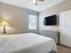 Cozy bedroom with window, dresser, and mounted television on a light-colored wall at 3709 Cedar Hammock Trl, St Cloud, FL 34772