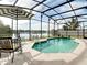 A clear, screened-in pool area with patio seating overlooking a beautiful lake at 3709 Cedar Hammock Trl, St Cloud, FL 34772