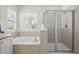Bright bathroom featuring a soaking tub beneath two windows and a glass enclosed walk-in shower at 785 Desert Mountain Ct, Reunion, FL 34747