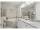 Bright bathroom featuring a double vanity, soaking tub, and glass-enclosed shower at 785 Desert Mountain Ct, Reunion, FL 34747