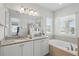 Bright bathroom featuring double sinks with granite counters, soaking tub, and walk-in shower at 785 Desert Mountain Ct, Reunion, FL 34747