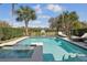 A private pool and spa are surrounded by lush landscaping and lounge seating on a sunny day at 785 Desert Mountain Ct, Reunion, FL 34747