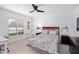 Cozy bedroom with a floral-patterned bedspread, a ceiling fan, and a large window at 808 Golfpark Dr, Celebration, FL 34747