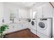 Well-lit laundry room featuring white cabinets, a sink, counter space and modern washer and dryer at 808 Golfpark Dr, Celebration, FL 34747