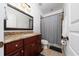 Bathroom with dark wood vanity, granite counters, shower with curtain and decorative mirror at 8437 Lake Burden Cir, Windermere, FL 34786